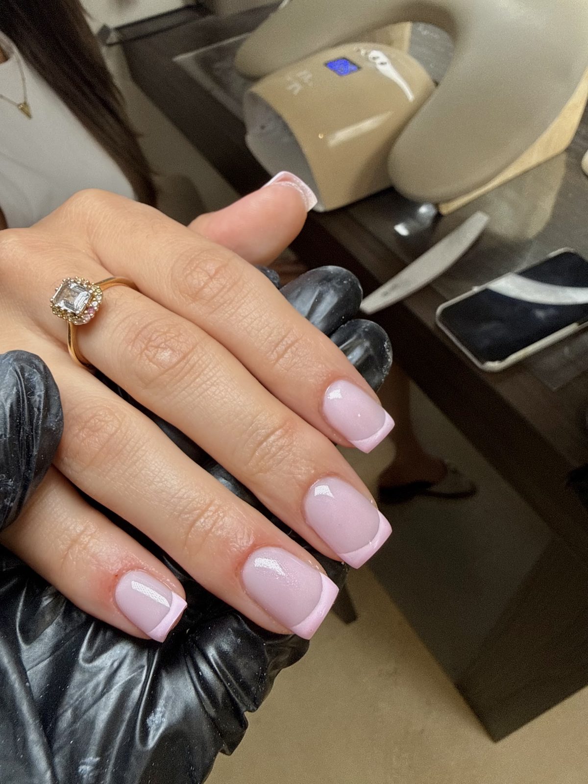 French buildergel met een witte smile line, de hand rust in een zwarte handschoen